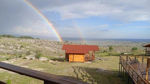 a rainbow over a log cabin with a house at Alma Serrana - Suites de montaña! in La Cumbrecita
