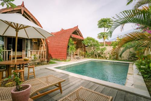 a villa with a swimming pool and a table with an umbrella at Matapalo Bungalows Uluwatu in Uluwatu