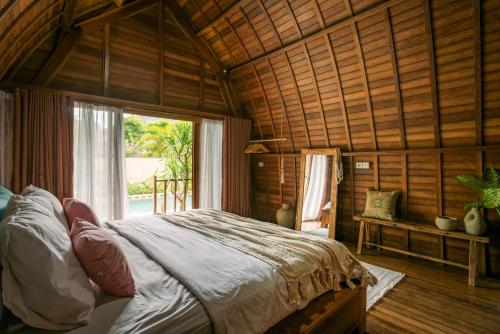 a bedroom with a bed in a room with a window at Matapalo Bungalows Uluwatu in Uluwatu