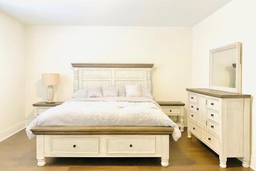 a bedroom with a white bed and a dresser and a mirror at Snow Valley Hideaway in Barrie