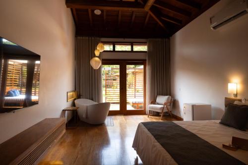ein Schlafzimmer mit einem Bett, einem Stuhl und einem Fenster in der Unterkunft Tiradentes Boutique Hotel in Tiradentes