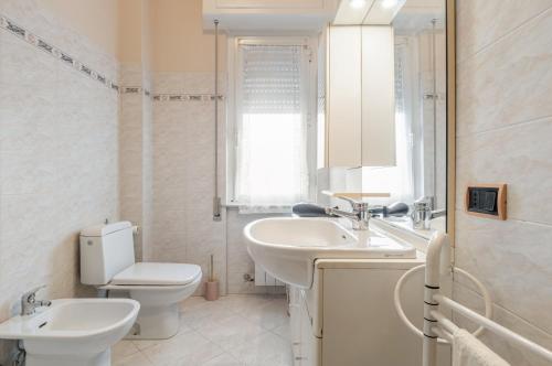 La salle de bains blanche est pourvue de toilettes et d'un lavabo. dans l'établissement Sailing Ships Cozy flat x5 with balcony, à La Spezia