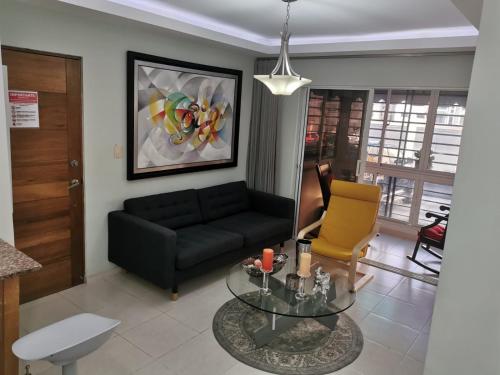 sala de estar con sofá negro y mesa de cristal en Altos de Alemeda, Santo Domingo Oeste, en Santo Domingo