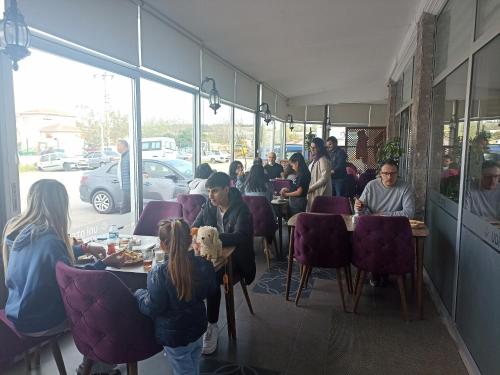 a group of people sitting at tables in a restaurant at Udi Hotel in Çanakkale