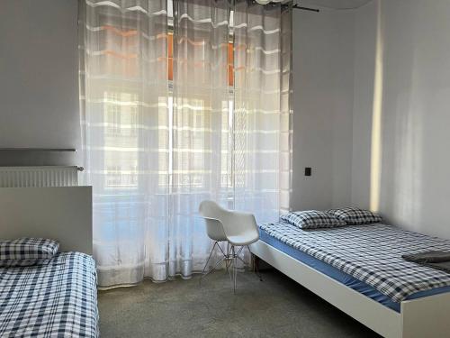 1 dormitorio con 2 camas, silla y ventana en Apart Lwowska, en Varsovia