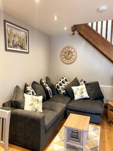 a living room with a couch and a clock on the wall at Cosy annex in the gateway to the lakes in Burneside