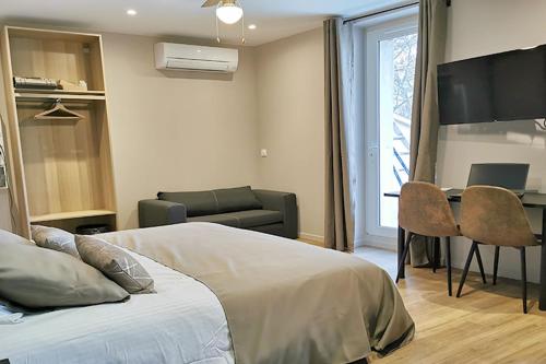 a bedroom with a bed and a table and a couch at Appart Hotel Spa Perpignan in Perpignan
