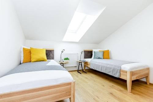 two beds in a room with white walls and wooden floors at KORZO Family in Lipno nad Vltavou