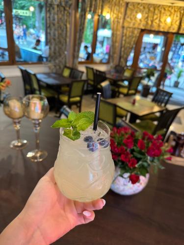 a hand holding a drink with a straw in a restaurant at Pensiunea Izvoare Olanesti 3*** in Băile Olăneşti