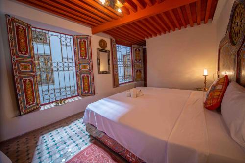 a bedroom with a large white bed with windows at Riad Fes Hayat - Confort Stay in Fès