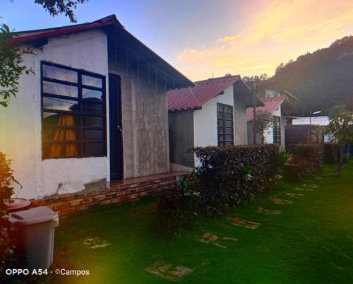 a small white house with a grass yard at CASA BAHAREQUE HOSPEDAJE in Monguí