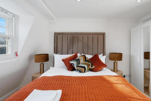 um quarto com uma cama laranja e 2 candeeiros em The Signature Residences em Londres