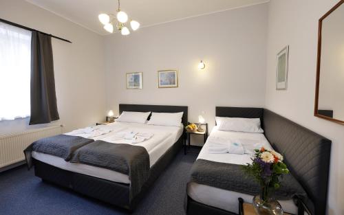 um quarto de hotel com duas camas e um vaso de flores em Hotel Boston em Karlovy Vary