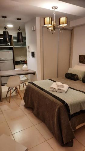 a bedroom with two beds and a kitchen and a table at MONOAMBIENTE SUNCHALES in Sunchales