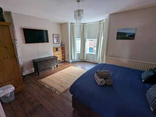 a bedroom with a blue bed and a television at Lavender House Weymouth in Weymouth
