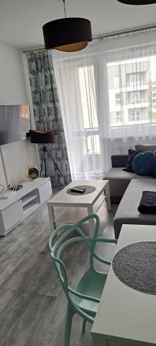 a living room with a green chair and a couch at Apartament Morski in Koszalin
