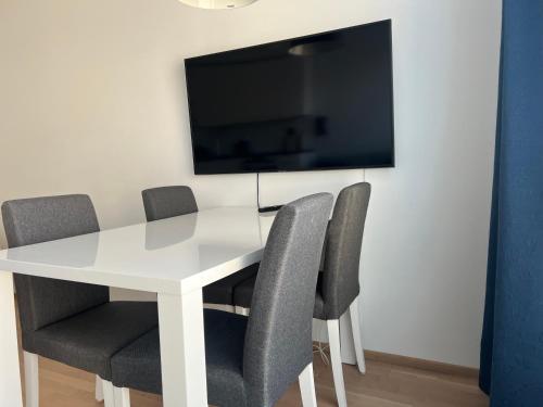 mesa blanca con sillas y TV en la pared en Kodikas keskustayksiö autohallipaikalla en Turku