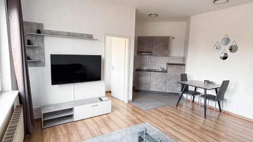 a living room with a table and a tv and a kitchen at E&B Apartments Korb in Korb