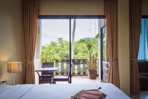 1 dormitorio con cama y vistas a un balcón en Panya Resort Koh Samui, en Choeng Mon Beach