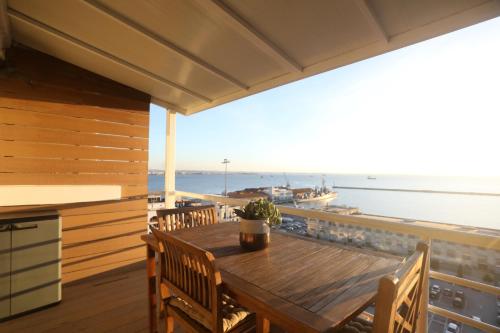 einen Holztisch auf einem Balkon mit Meerblick in der Unterkunft cloud9-skg in Thessaloniki
