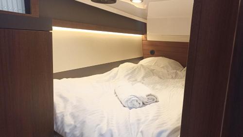 - un lit avec des draps blancs et une serviette roulée dans l'établissement Jacht łódź Northman 1200-elektryczny, à Bartkowa-Posadowa