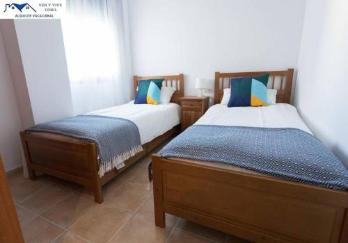 2 camas individuales en una habitación con ventana en APARTAMENTO TREBUJENA, en Conil de la Frontera