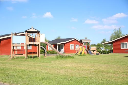 a playground with a slide in a yard with houses at Camping de Kuilen in Someren