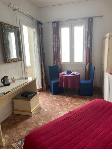 een slaapkamer met een tafel en blauwe stoelen en ramen bij Casa Sulla Laguna in Murano