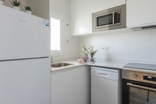 eine weiße Küche mit einer Spüle und einer Mikrowelle in der Unterkunft Feel Welcome Barcelona in Cornellà de Llobregat