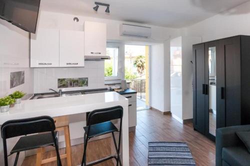 a kitchen with white cabinets and a kitchen island with chairs at Ellena Sunshine in Opatija