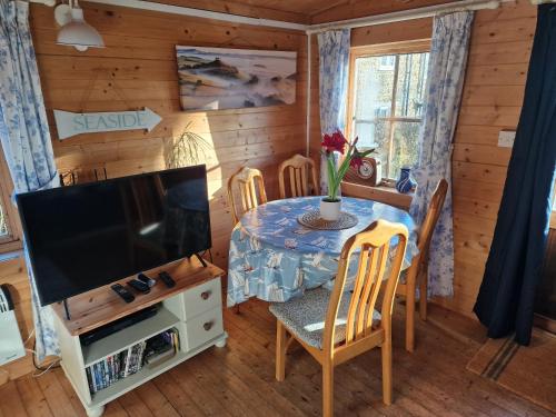 a dining room with a table and a television at Cherry Orchard Retreat in Chideock