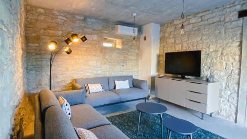 sala de estar con sofá y TV en Villa Kalu in Central Istria for 6 people with private pool, en Mrgani