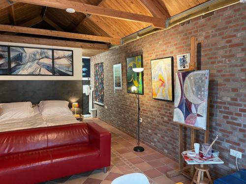 1 dormitorio con cama de cuero rojo en una pared de ladrillo en 't ouw ateljeeke, en Budel