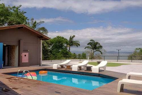 a swimming pool with white chairs and a house at Lindo Coliving a Beira Mar no João Paulo in Florianópolis