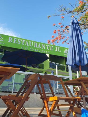 a couple of wooden tables and an umbrella at Pousada Amendoeira in Mangaratiba