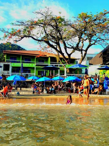 a group of people in the water at a beach at Pousada Amendoeira in Mangaratiba