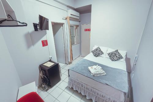 a small room with a bed and a television at Hotel Apiacas in Ribeirão Preto