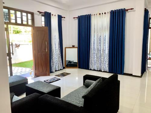 a living room with two couches and blue curtains at Ocean Bliss Villa Mirissa in Kamburugamuwa