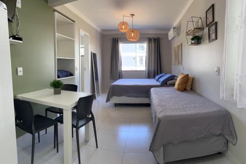 1 dormitorio con 2 camas, mesa y escritorio en Residencial Rumo ao Mar - Bombinhas-SC, en Bombinhas