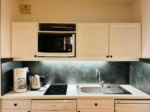 une cuisine avec un évier et un micro-ondes dans l'établissement Appartement cosy 4 pers. à Valloire, proche centre & pistes, balcon, parking, casier à skis - FR-1-263-529, à Valloire