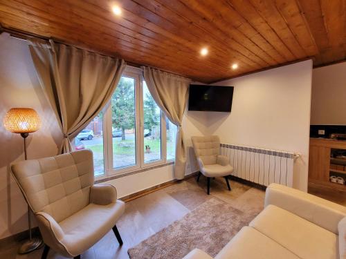 uma sala de estar com duas cadeiras e uma janela em Chalé Zimbro, Serra da Estrela, Penhas da Saúde em Penhas da Saúde