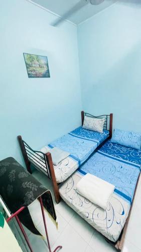 a room with two beds and a chair in it at Homestay Port Dickson in Port Dickson