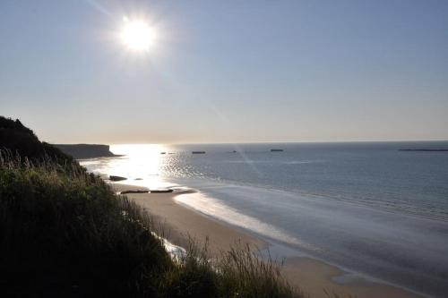a beach with the sun rising over the water at L'Ancre du Bessin - Proximité Bayeux et plages du débarquement - D-DAY - Spa en option - Accessible PMR in Saint-Vigor-le-Grand
