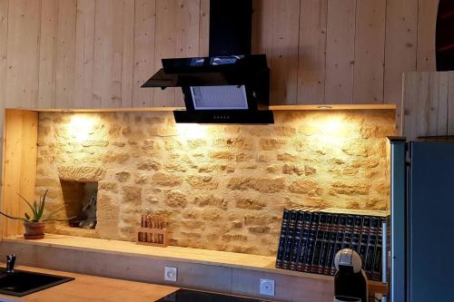 a kitchen with a counter with a stone wall at L'Ancre du Bessin - Proximité Bayeux et plages du débarquement - D-DAY - Spa en option - Accessible PMR in Saint-Vigor-le-Grand
