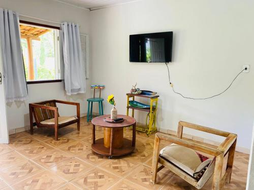 sala de estar con sillas, mesa y TV en Caraiva Hostel, en Caraíva