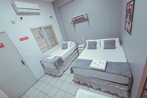 a small room with two beds and a window at Hotel Apiacas in Ribeirão Preto
