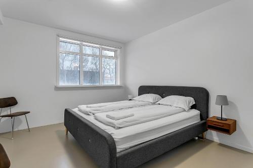Cama en habitación blanca con ventana en Spacious and Central Apartment - 3 Bedrooms, en Reikiavik
