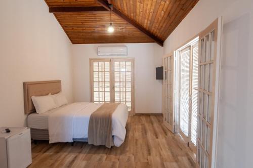 a bedroom with a bed and two windows at Pousada Mar de Geribá in Búzios