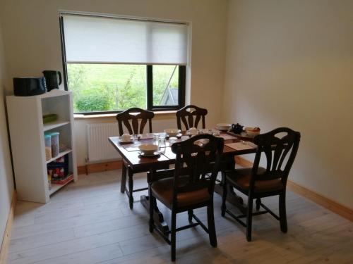 Greatlawne في كيلارني: غرفة طعام مع طاولة وكراسي ونافذة