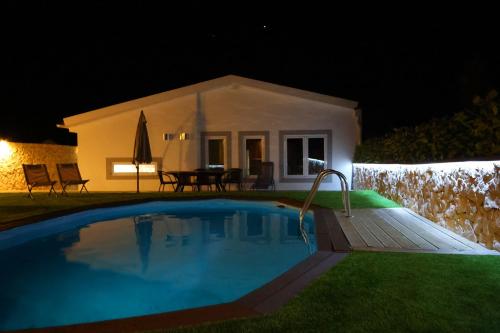 uma piscina em frente a uma casa à noite em Da Serra guesthouse em Porto de Mós